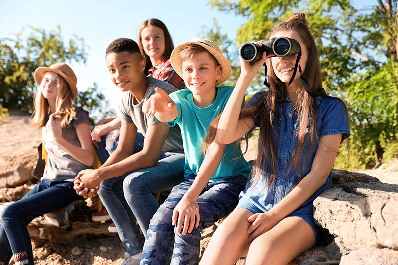 Kinder beobachten in der Natur mit einem Fernglas die Umgebung
