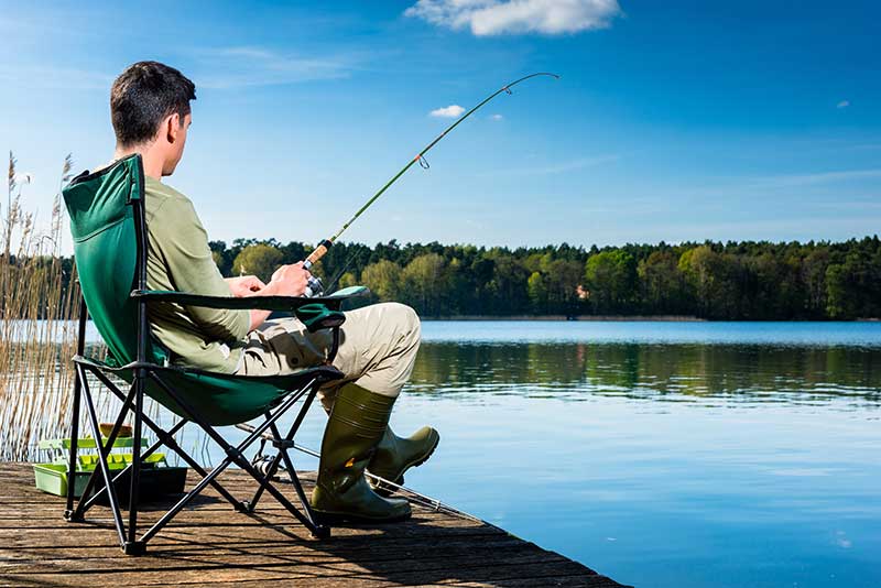 Mann sitzt am See und Angelt in Ruhe