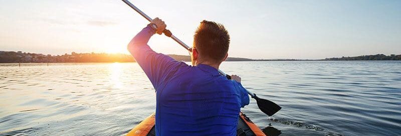 Ein Sportler paddelt auf einem See in den Sonnenuntergang Sport Wassersport Mann