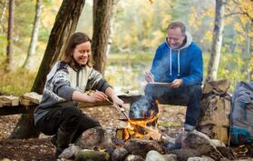 Eine Frau und ein Mann machen über dem Lagerfeuer im Wald ein Essen