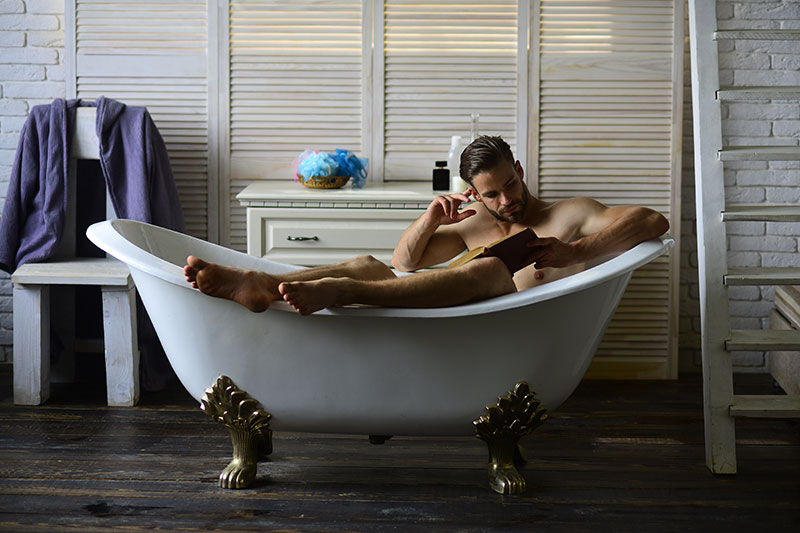 Mann-sitzt-in-einer-Badewann-und-liest-ein-Buch