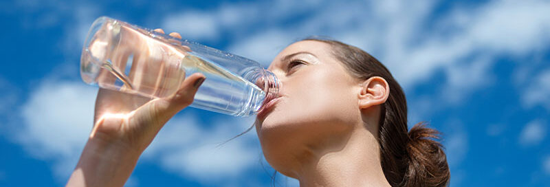 Frau trinkt Wasser aus einer Flasche