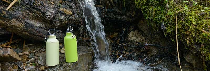 Wasserfall mit Trinkflaschen im Wald