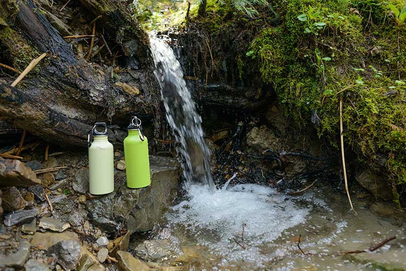 Wasserfall mit Trinkflaschen im Wald