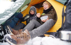 Zelten unter Schnee mit Wasserkocher im Winter
