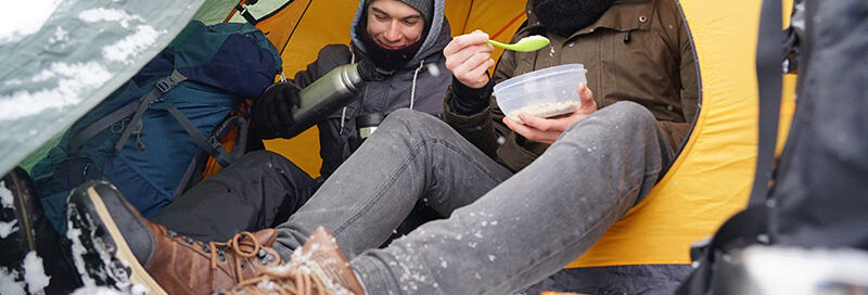 Zelten unter Schnee mit Wasserkocher im Winter