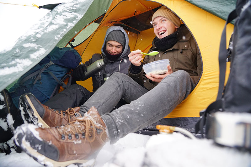 Zelten unter Schnee mit Wasserkocher im Winter