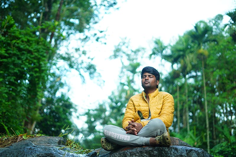 Mann sitzt bei einer Meditation im Wald