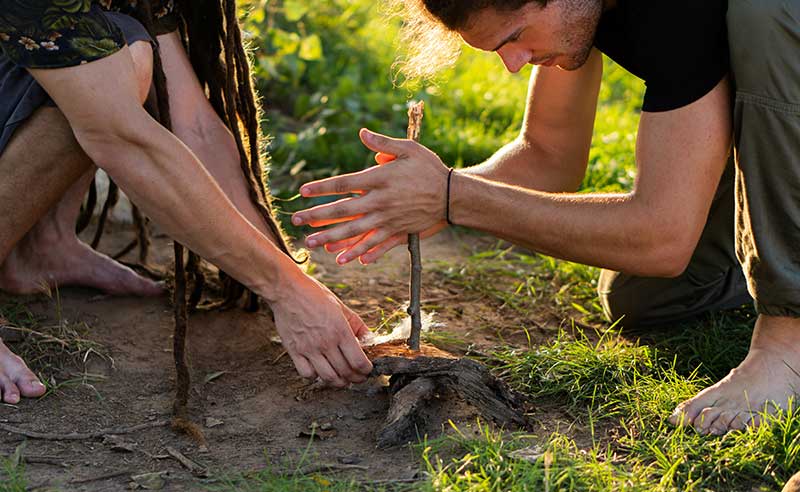 Naturfreunde machen mit Bow Drill ein Lagerfeuer