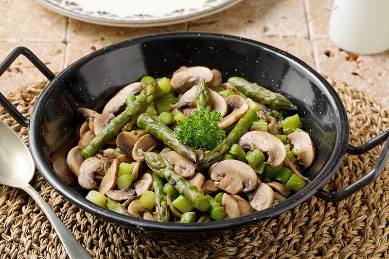 vegetarisches Gericht mit Spargel und Pilze in der Pfanne